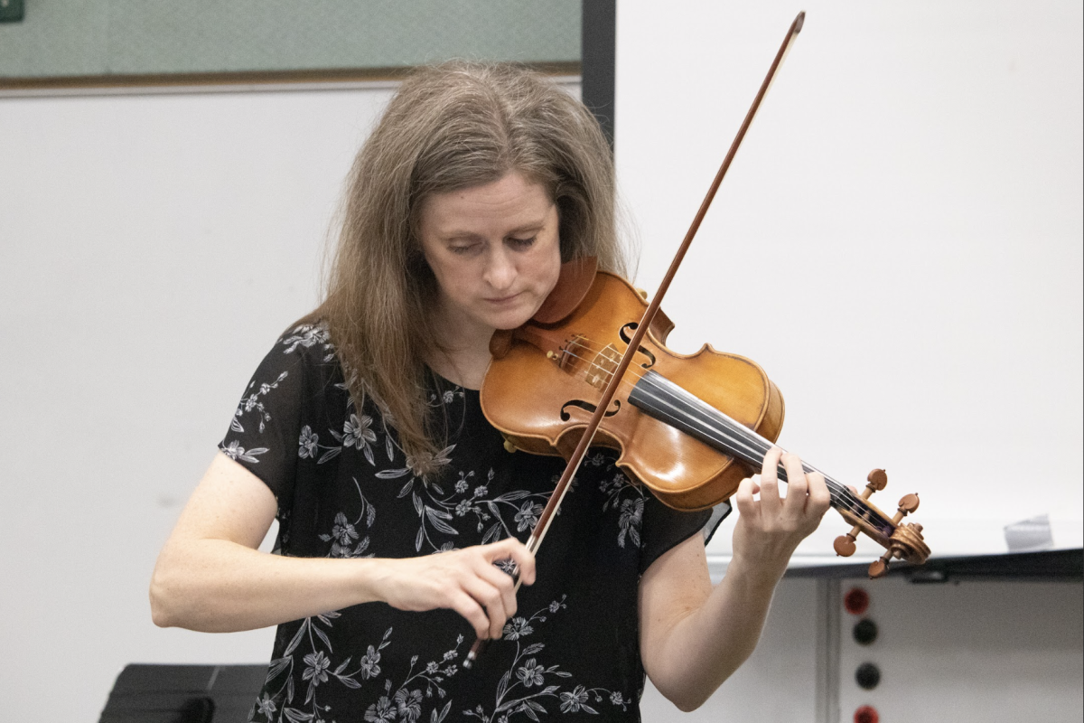 Playing the violin, Ms. Herron, the new orchestra teacher, demonstrates to her class how to play a piece. “I was a little nervous going into [the first day], of course, but it was just so much fun and so welcoming from the students,” Herron said. 